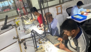 Artisans filing and soldering jewelry at workbenches in the Millennium Jewellery factory